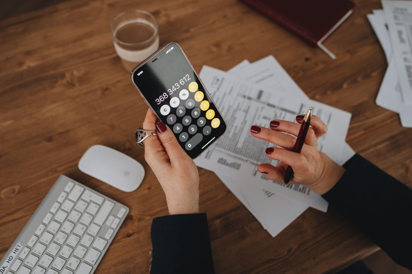 Hands using a finance app on a phone beside receipts